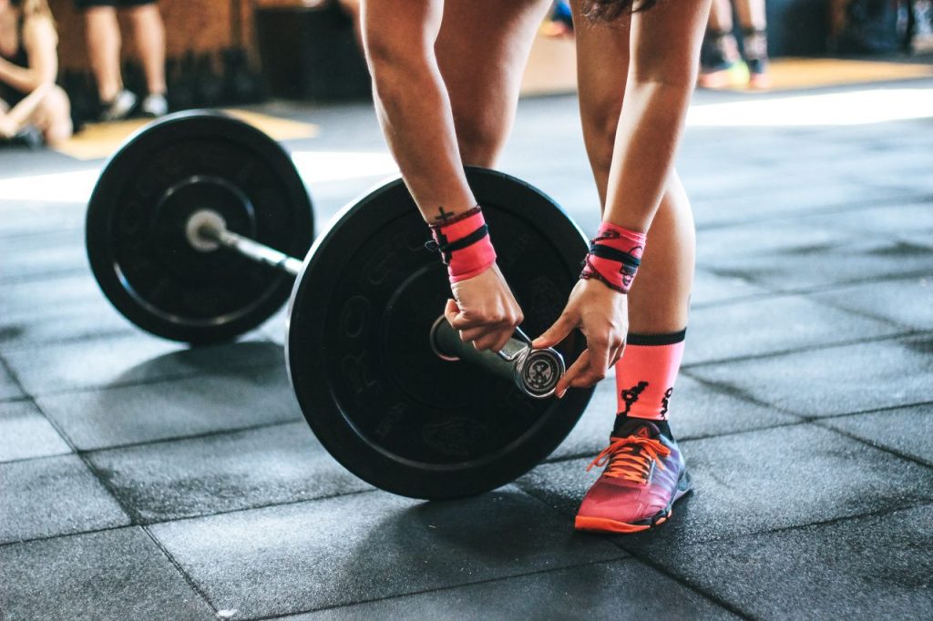pexels-photo-703014-703014 Athlete tightening barbell plates in a gym, emphasizing fitness and strength.